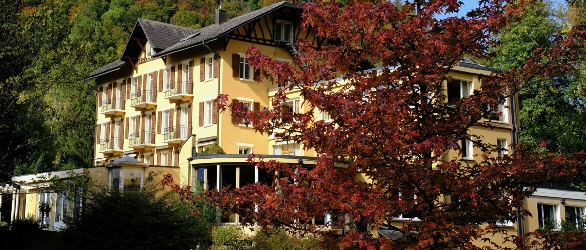 Le Foyer de Charité Dents-du-Midi en automne, façade jaune et érable rouge