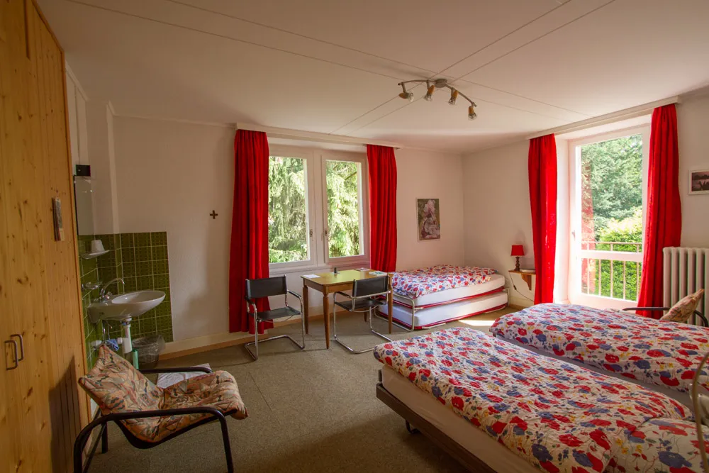 Chambre familiale — plusieurs lits, lavabo, vue sur le jardin