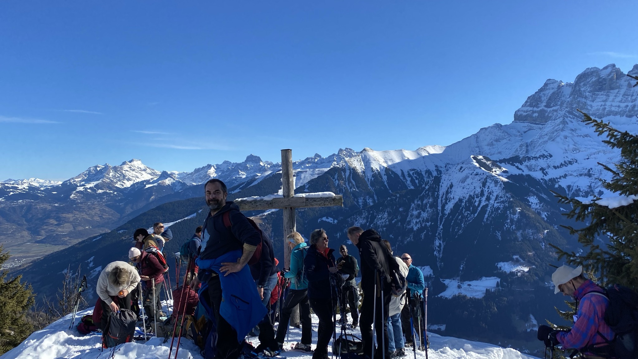 Groupe de retraitants à la croix sommitale avec vue panoramique sur les Dents-du-Midi en hiver