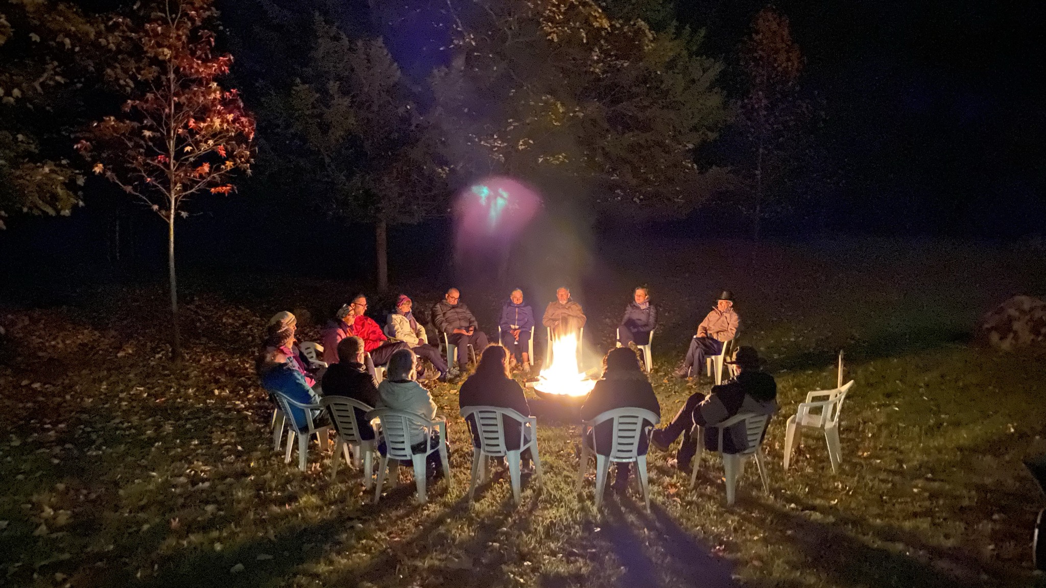 Groupe de retraitants réunis autour d'un feu de camp, veillée au Foyer