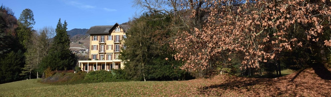Le bâtiment historique du Foyer de Charité Dents-du-Midi en automne, entouré d'arbres